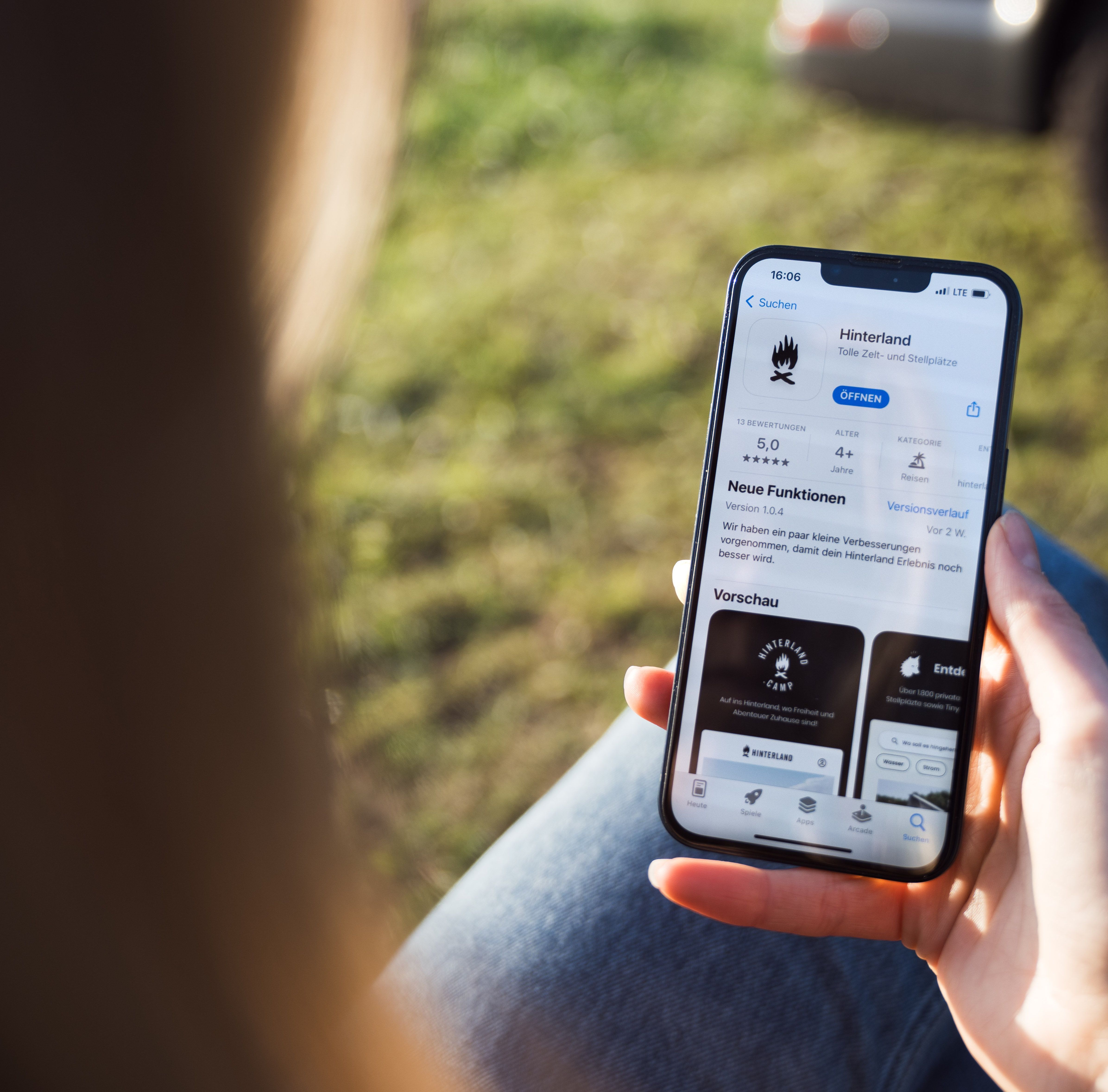 Frau hält ein Handy in der Hand, auf dem die beste Wohnmobilstellplatz-App im App-Store geöffnet ist