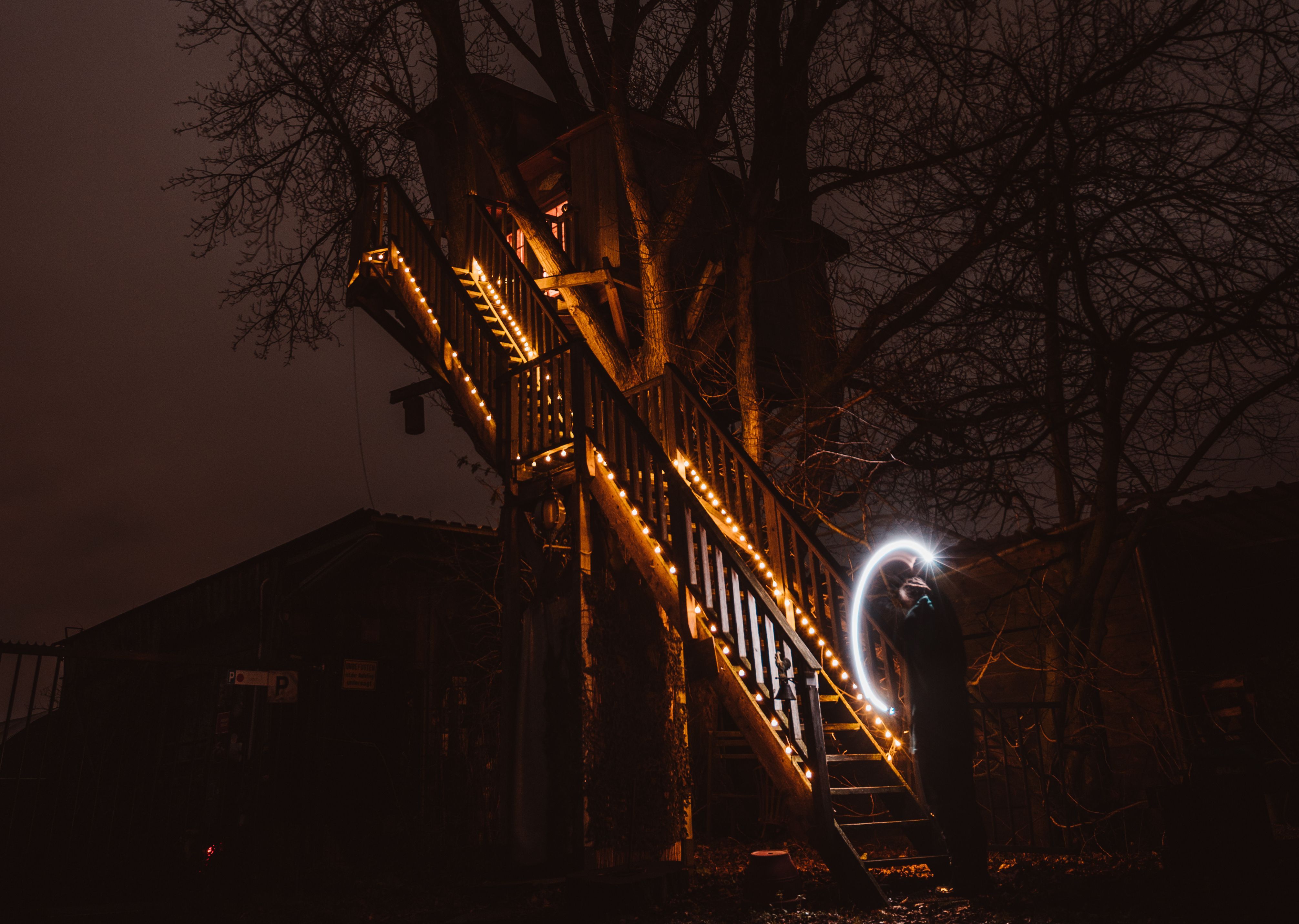 Baumhaushotel im Dunkeln, schön beleuchtete Treppe und Lichtspiel mit Taschenlampe