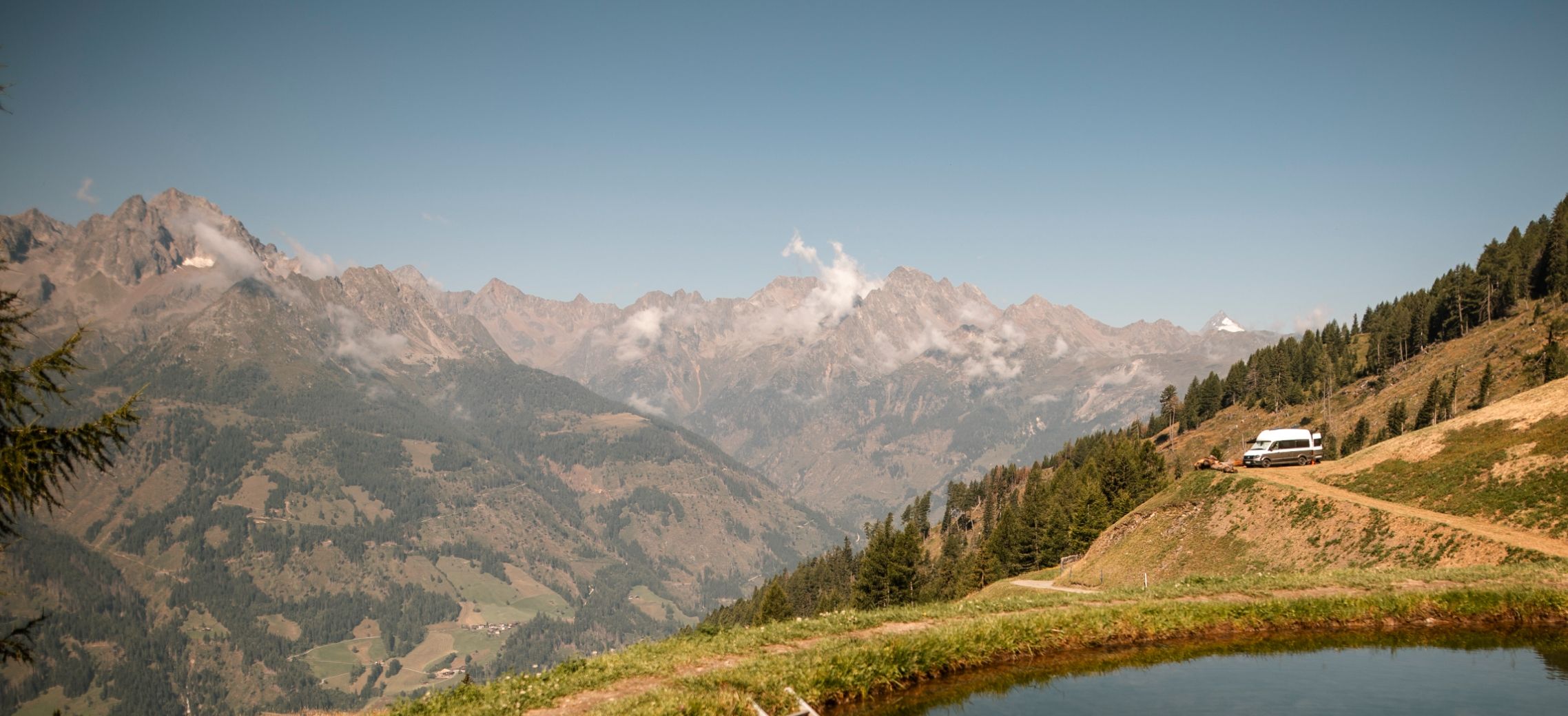 Womo, Camper, Van steht auf einem Camping-Stellplatz in den Bergen und direkt am See