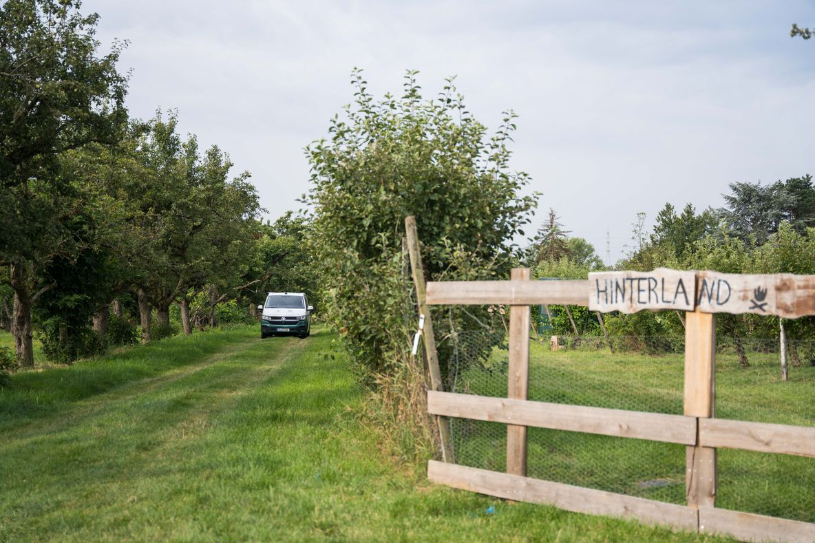 Ein Van steht mitten in der Apfelplantage auf einem Hinterland-Camp
