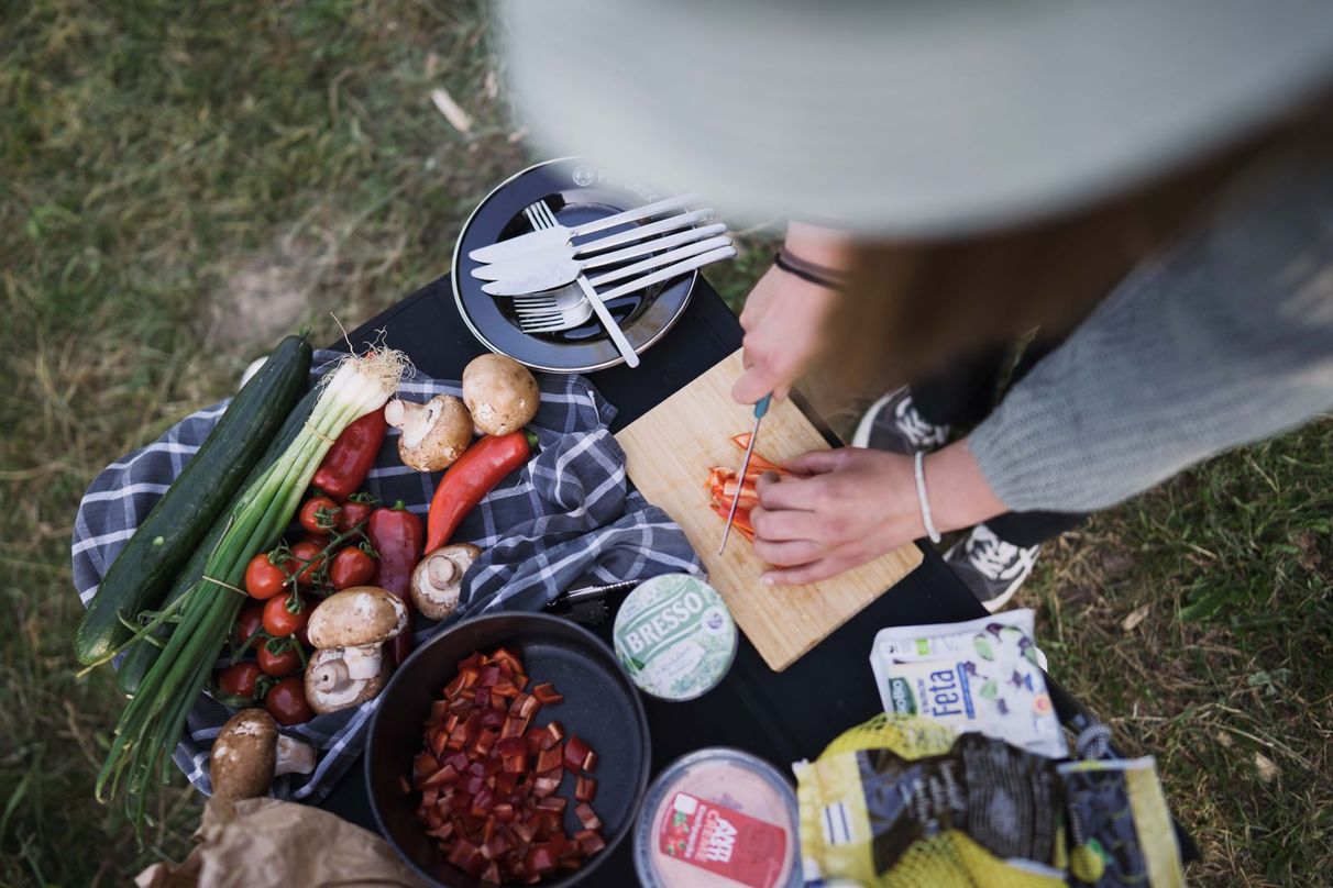 Frau beim Schneiden von Gemüse in der Camping-Outdoor-Küche