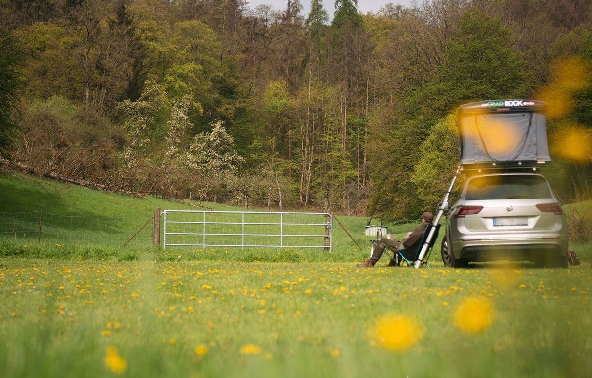 Auto mit Dachzelt steht auf einer Blumenwiese, auf einem Hinterland Camping Stellplatz in Alleinlage