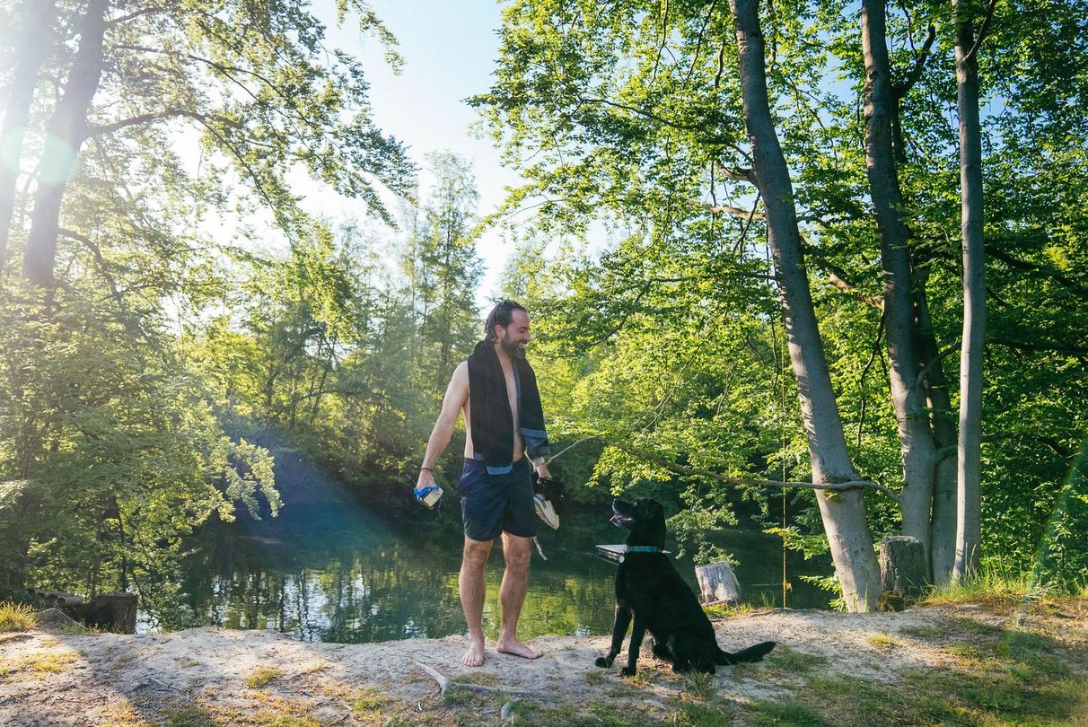 Mann und Hund haben gebadet im See an ihrem Stellplatz in Alleinlage und stehen vor dem Wasser
