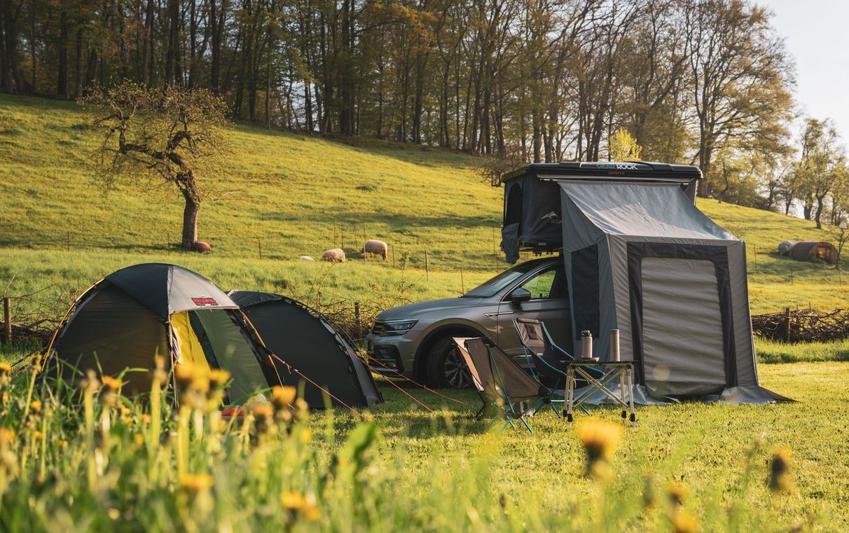 Camper / Auto mit Dachzelt steht auf einer grünen Wiese mit Blumen, es ist ein Camping Stellplatz von hinterland.camp in Alleinlage