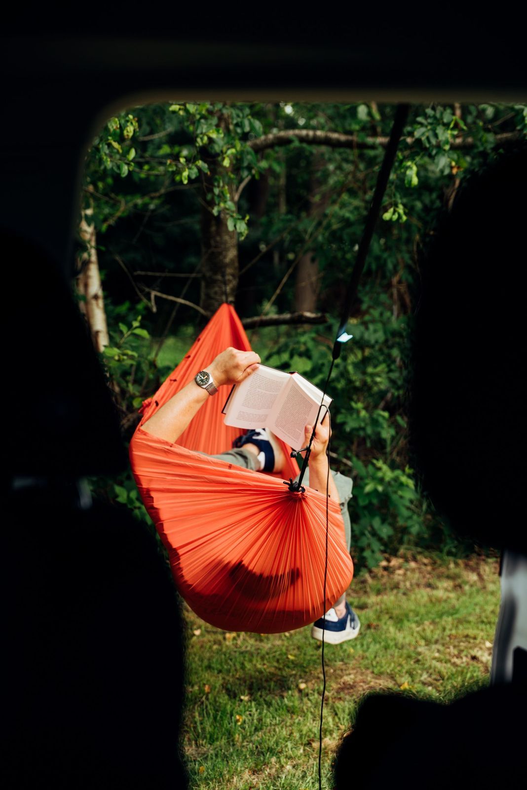Blick aus einem VW-Camper des Walden-Magazins: Es ist ein Mann zu sehen, der in einer Hängematte ein Buch liest