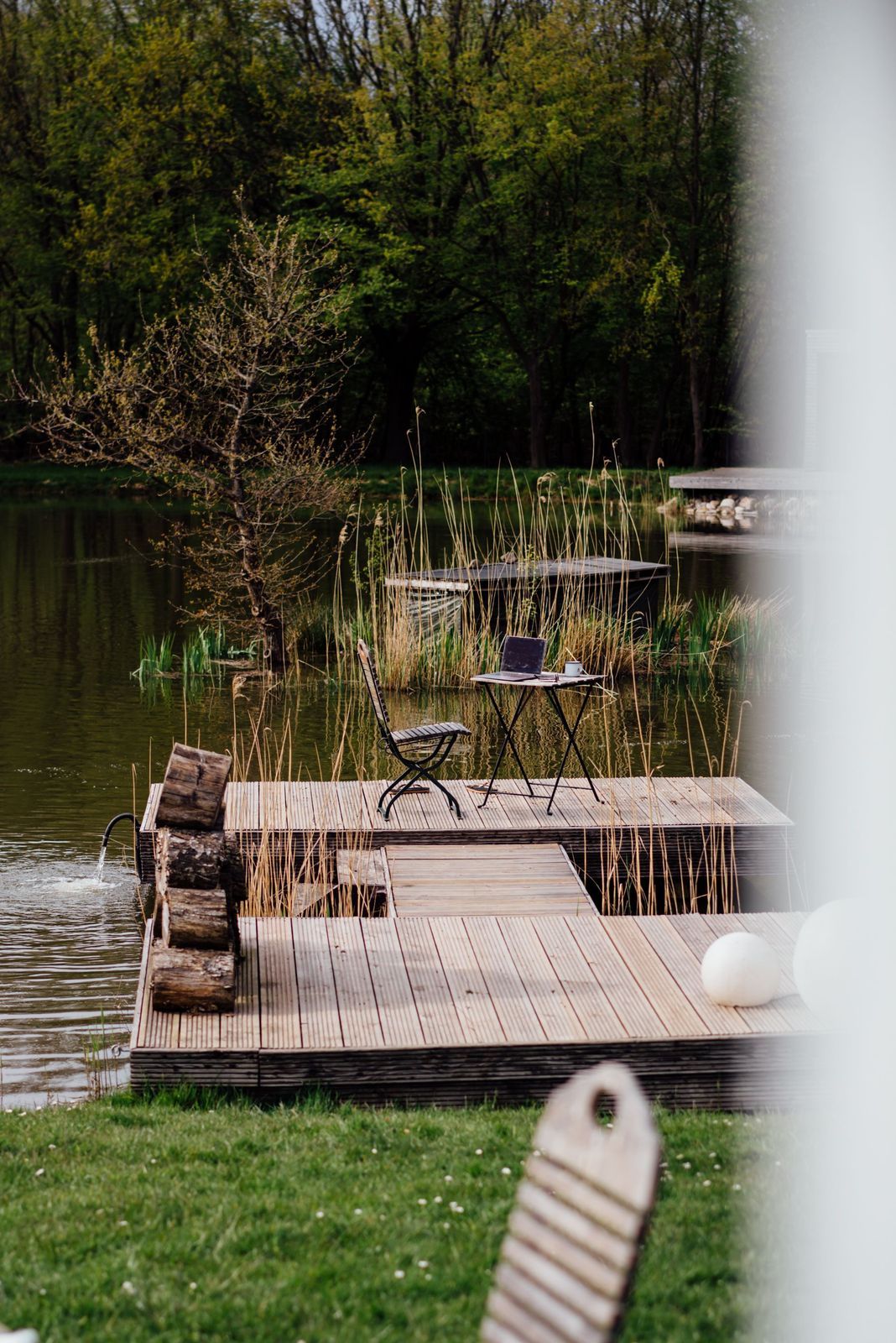 Stuhl und Tisch stehen zur Workation auf einem Steg bei einem See auf Privatgrund, es ist ein inserierter Platz zum Buchen einer Campingübernachtung bei hinterland.camp