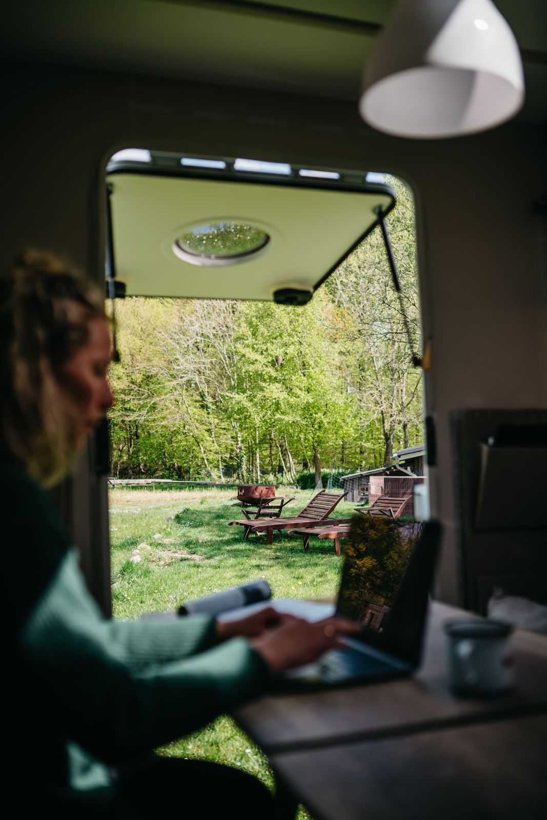 Frau macht workation am Laptop auf einem Stellplatz von hinterland.camp