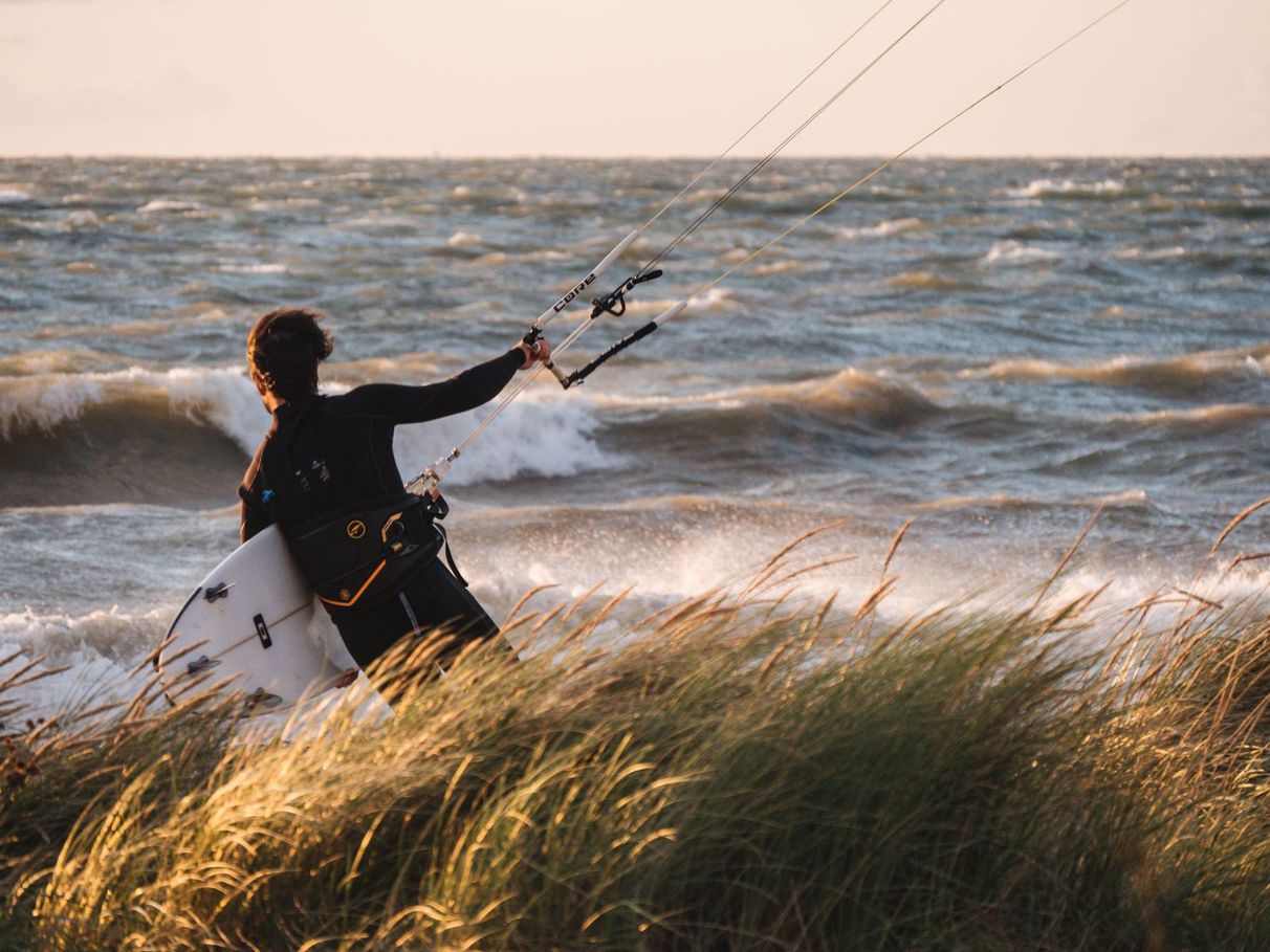 Hinterland Mitarbeiter Oli beim Kite-Surfen an der Nordsee hinter den Dünen vor dem Meer