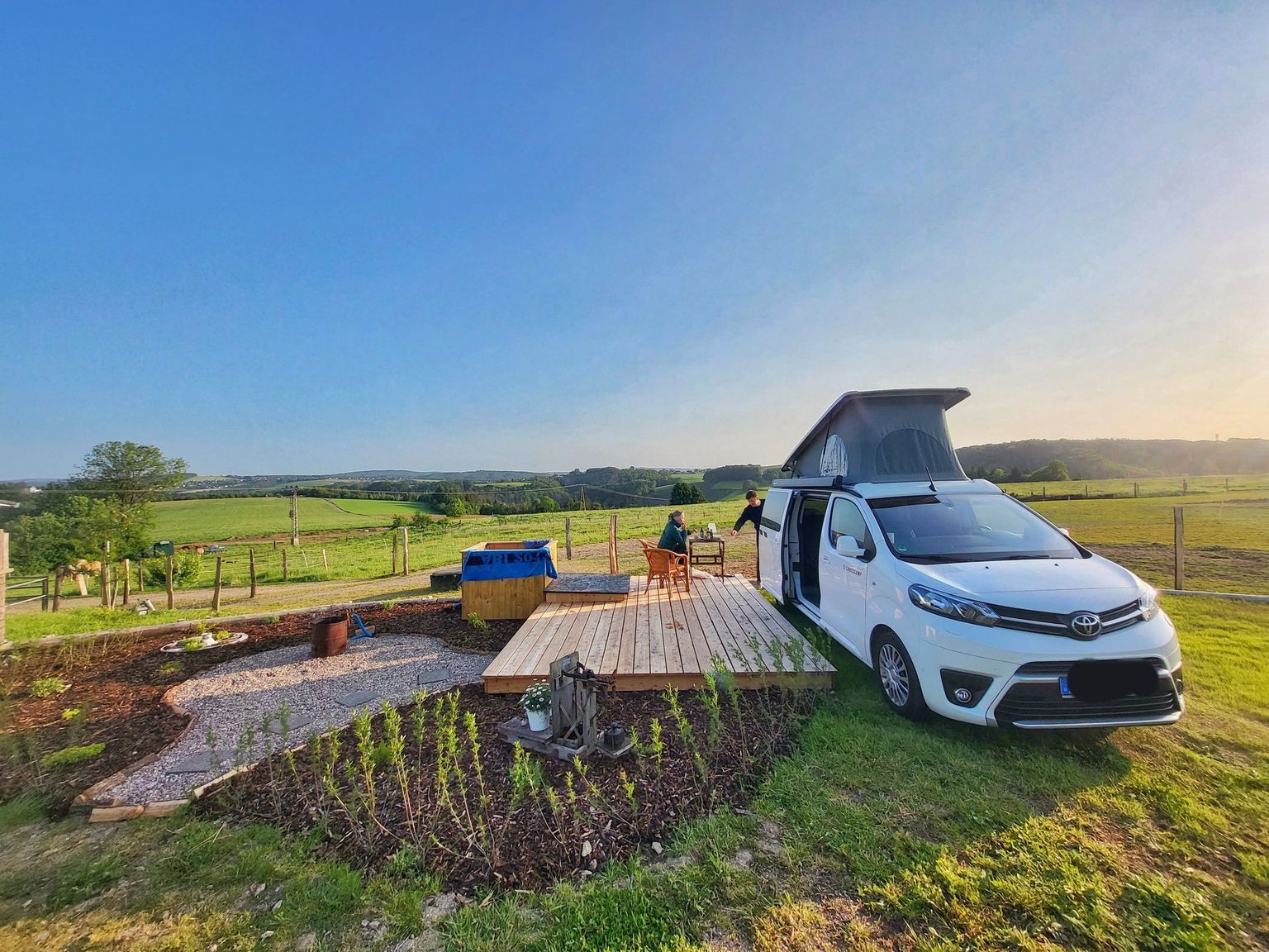 Camper steht an der Sonnen-Terrasse und dem Hot-Tub des Wellness-Campingplatzes von hinterland.camp