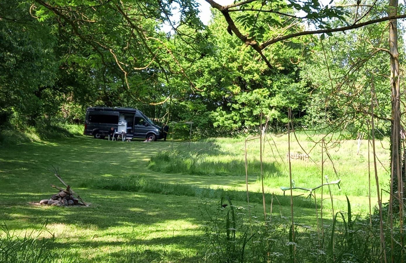 Stellplatz mitten im Grünen umgeben von Wald und Wiesen, Camper steht auf einer Wiese, die als Stellplatz bei hinterland.camp buchbar ist und in unmittelbarer Nähe zur Ostsee ist