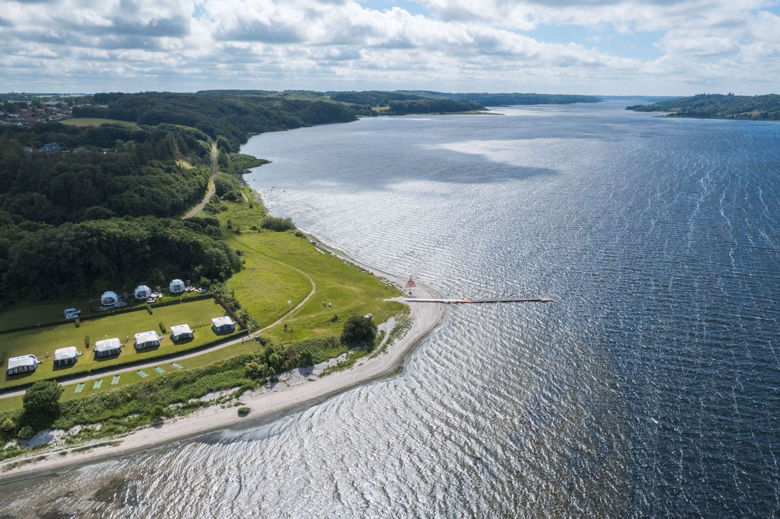 Luftaufnahme Mariagerfjord mit Glamping-Zelten direkt am Meer, die man über hinterland.camp buchen kann.