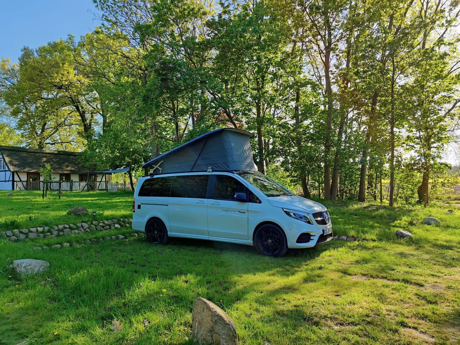 Camper steht auf einem Wellness-Campingplatz, idyllisch gelegen zwischen Feldern und Bäumen