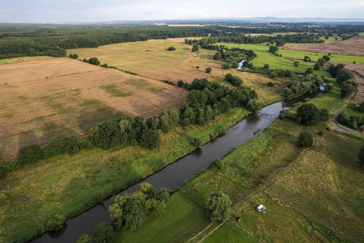 Drohnen-Aufnahme von einem Fluss umgeben von Feldern und Wäldern