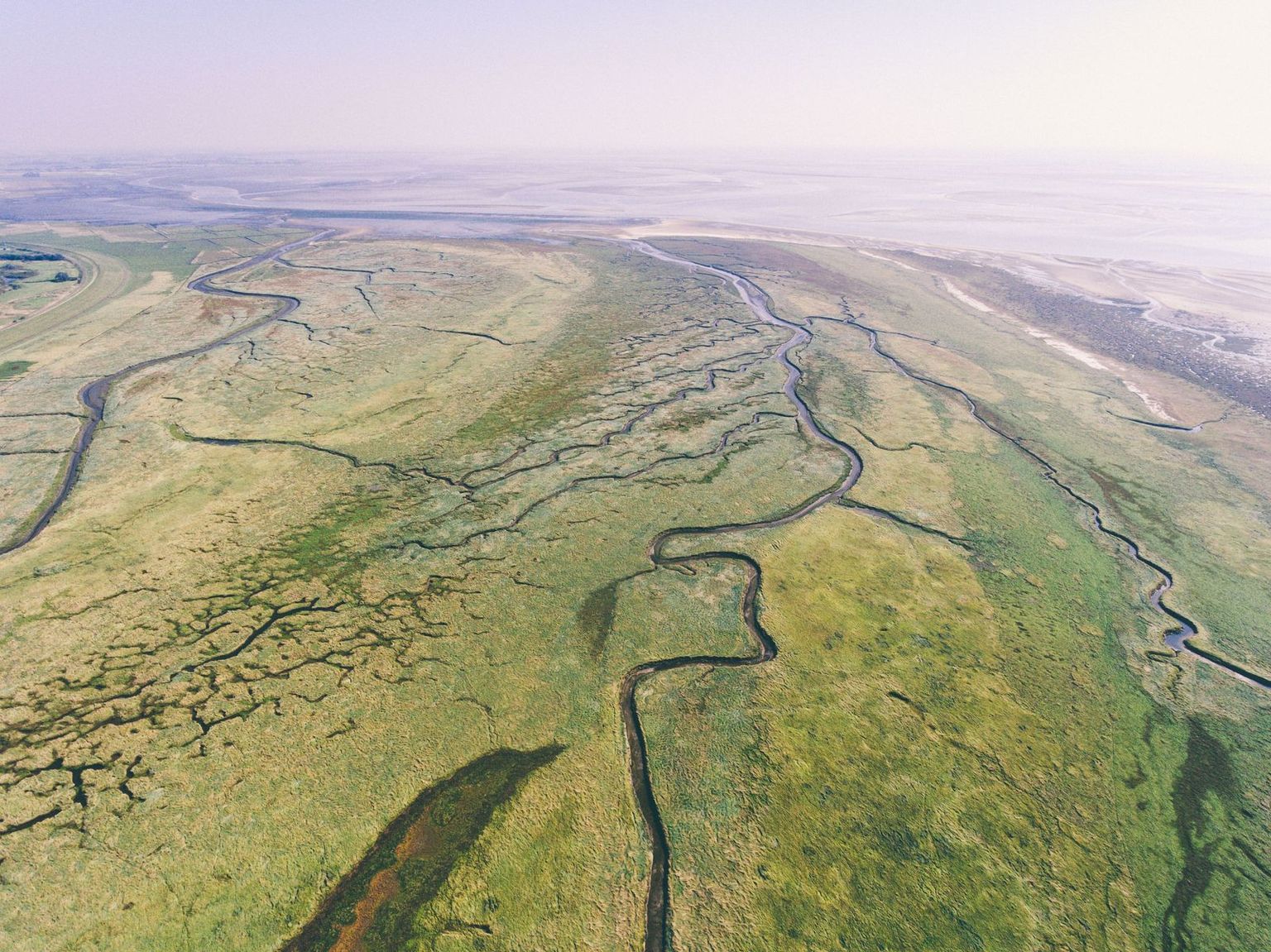 Drohnenaufnahme von der außergewöhnlichen Landschaft des Nordens mit der Nordsee, grünen Wiesen, Wattlandschaft und Flüssen