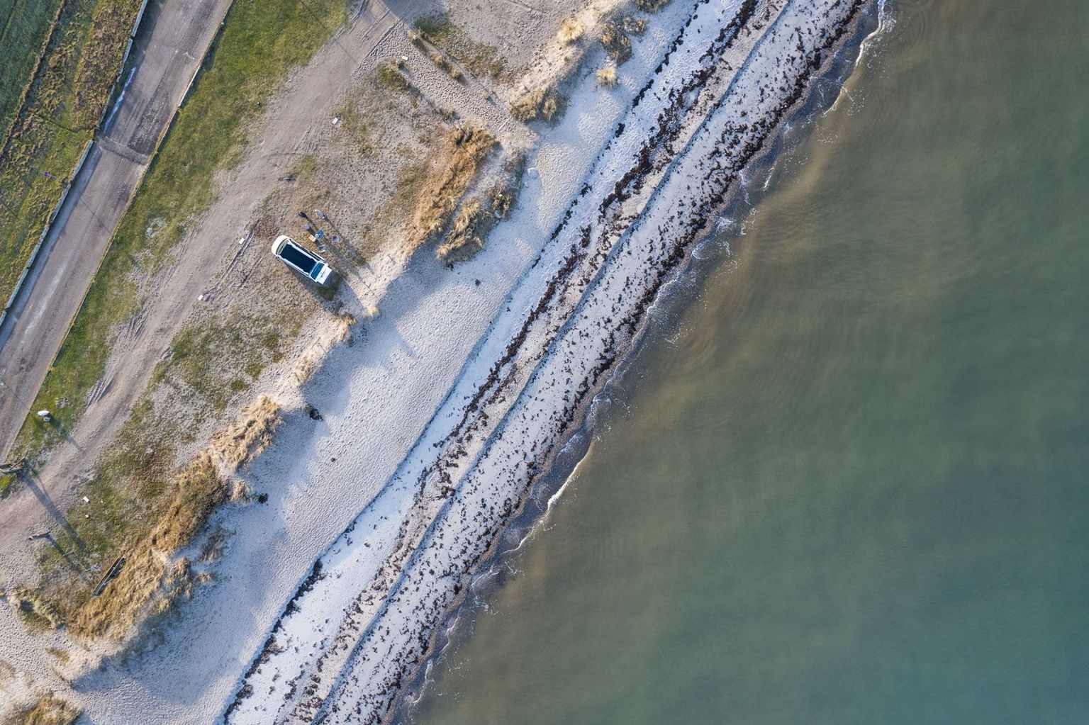 Vogelperspektive eines Vans, der am Strand der Ostsee parkt, direkte Lage am Wasser/Meer