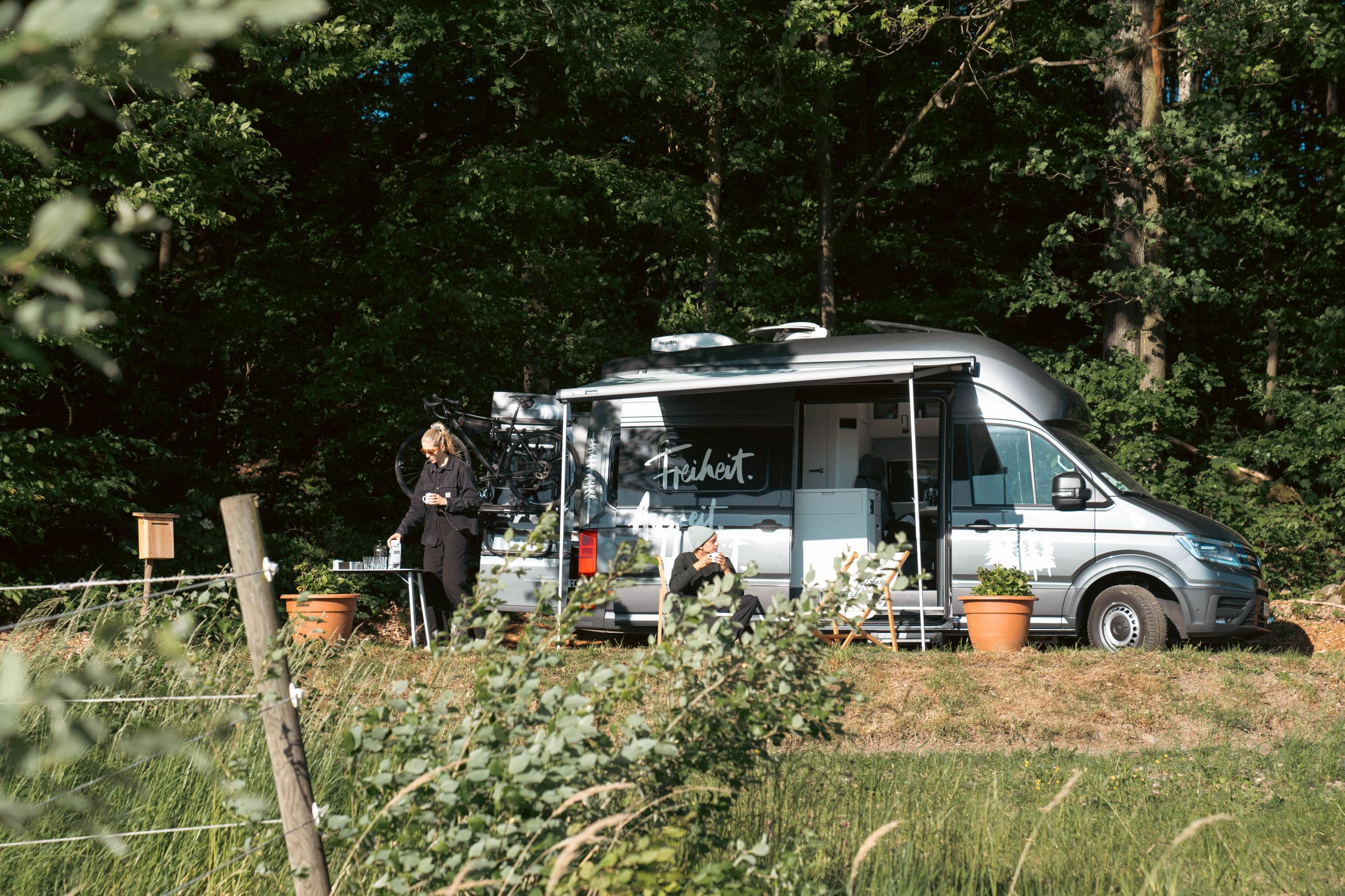 VW-Camper steht auf einem Wohnmobilstellplatz in der Natur auf einer Wiese