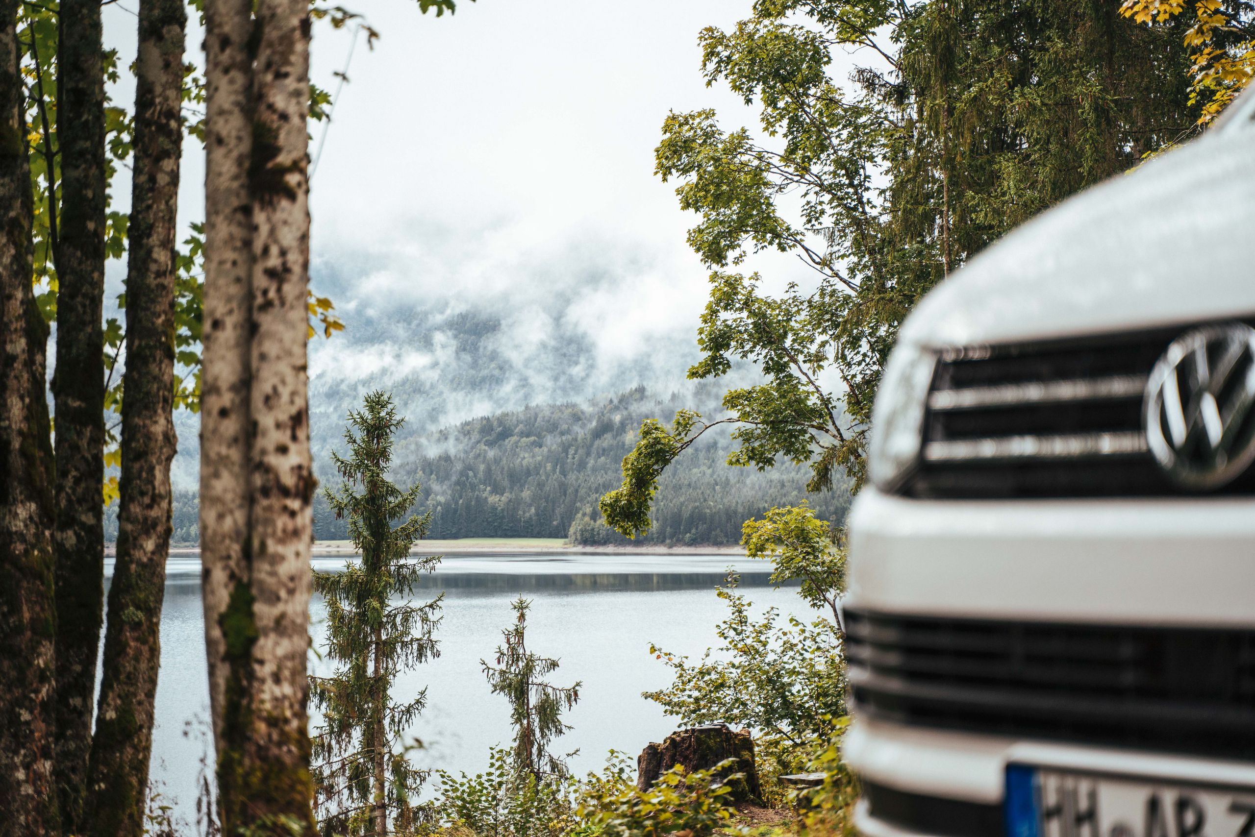 VW Camper an einem See im Wald
