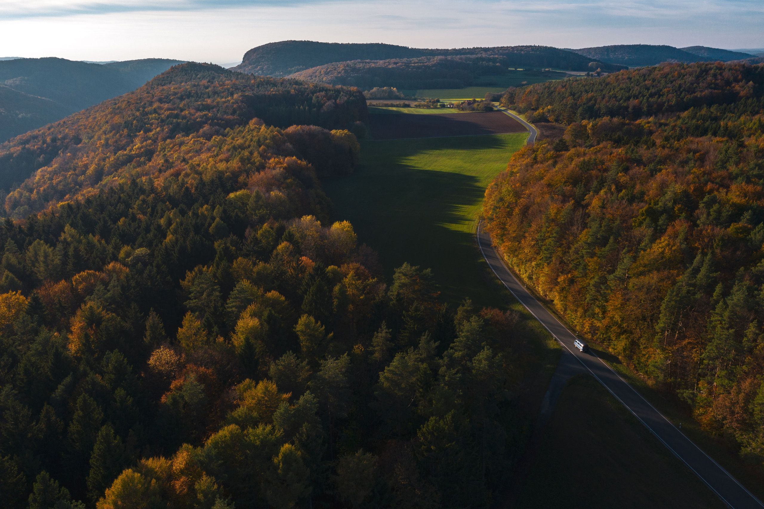 Schönes Panorama von Bayern im Herbst. Ein Auto fährt auf einer kurvigen Straße zu einem Zeltplatz im Bayern.