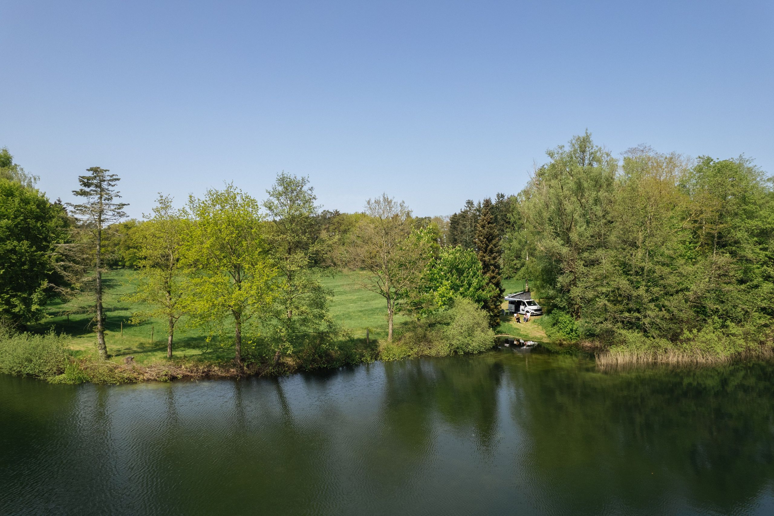 Camper steht auf einem Minicampingplatz direkt an der Wasserkante eines Sees in Alleinlage. Man kann den Minicampingplatz direkt bei hinterland.camp buchen.