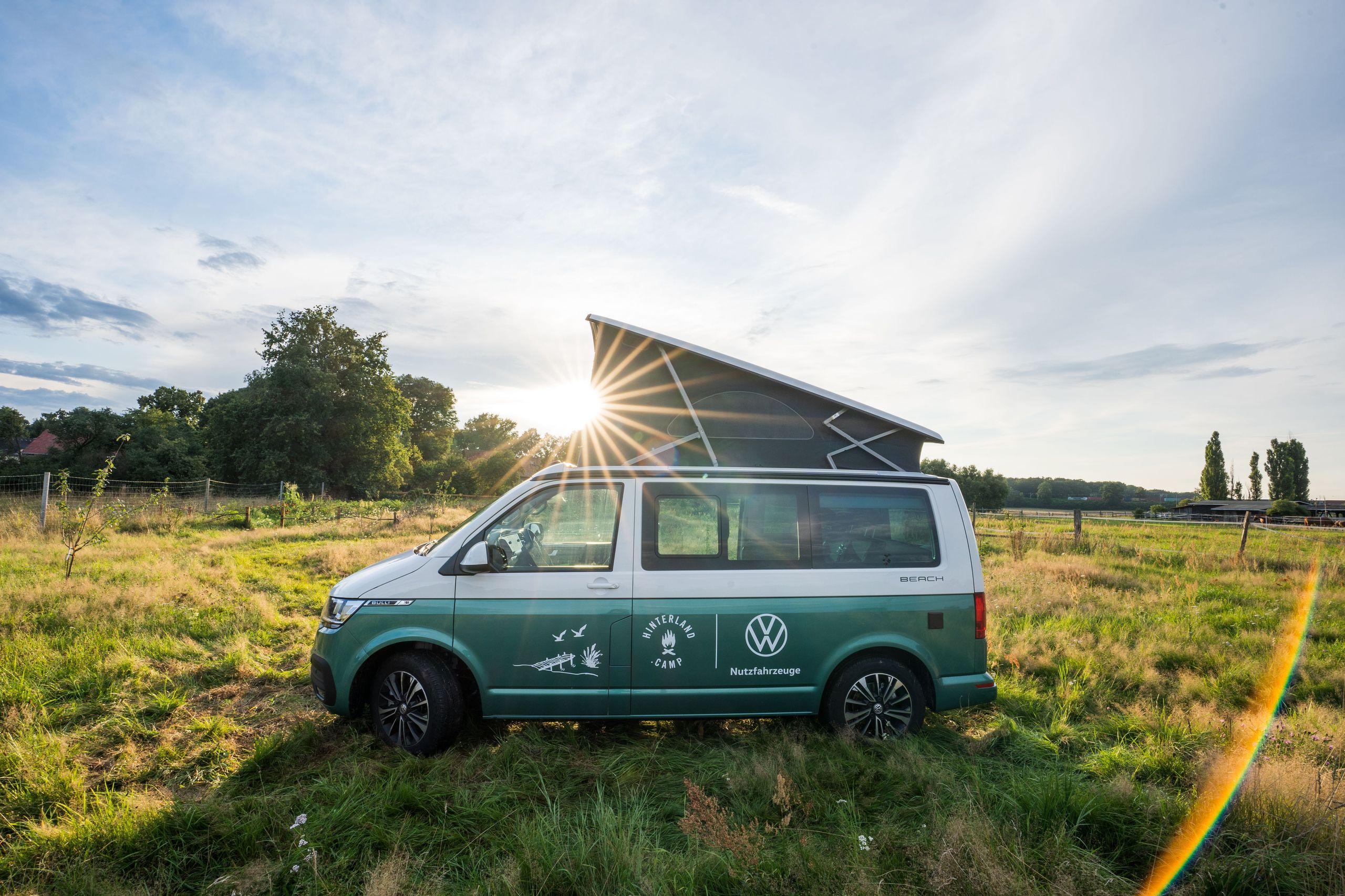 Ein VW-Camper steht auf einer Wiese vor einer Pferdekoppel, die zum Natur-Campingplatz in der Lüneburger Heide gehört.