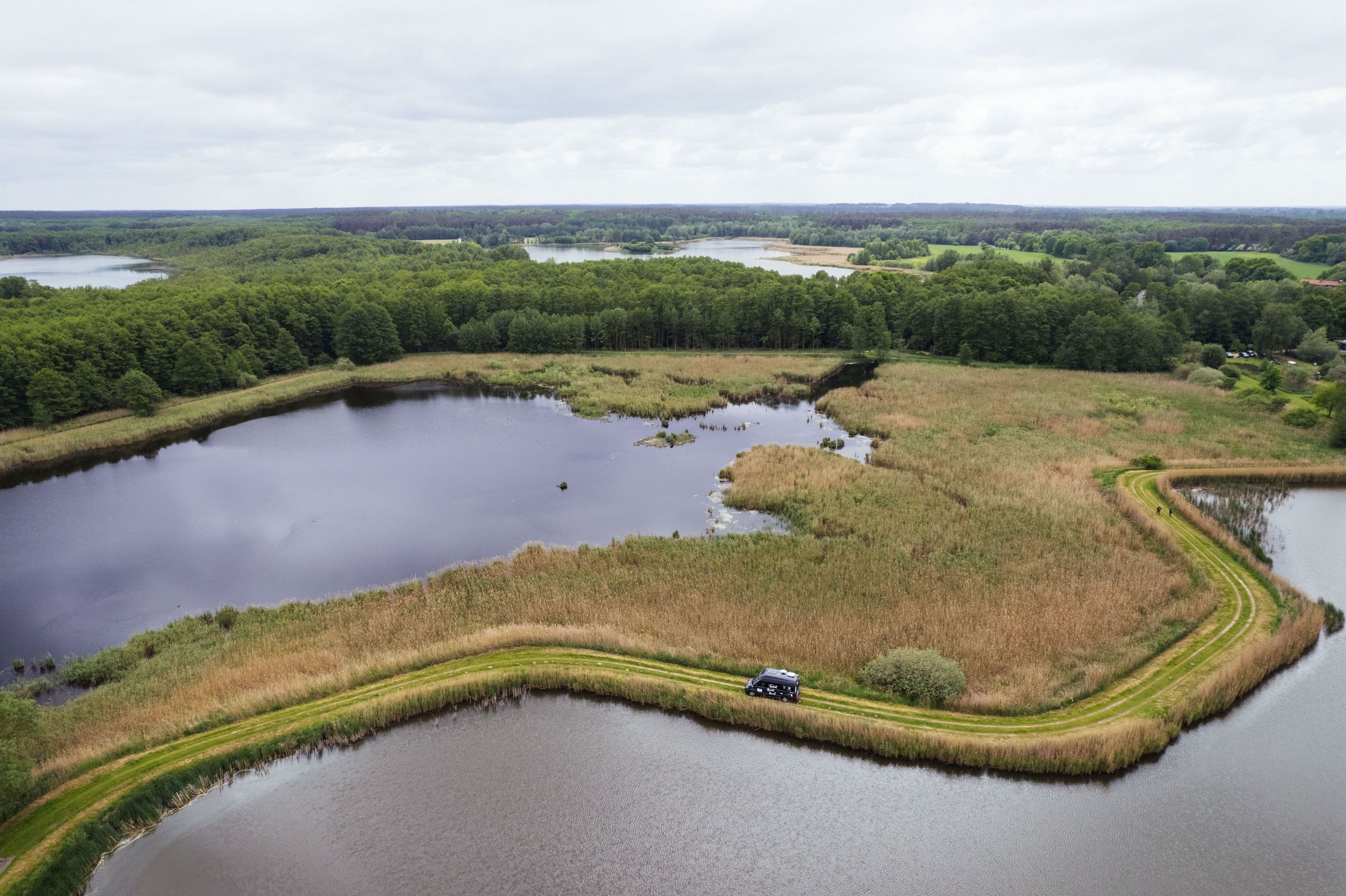 Drohnenaufnahme eines Camping Stellplatzes umgeben von Seen an der Müritz, buchbar bei hinterland.camp
