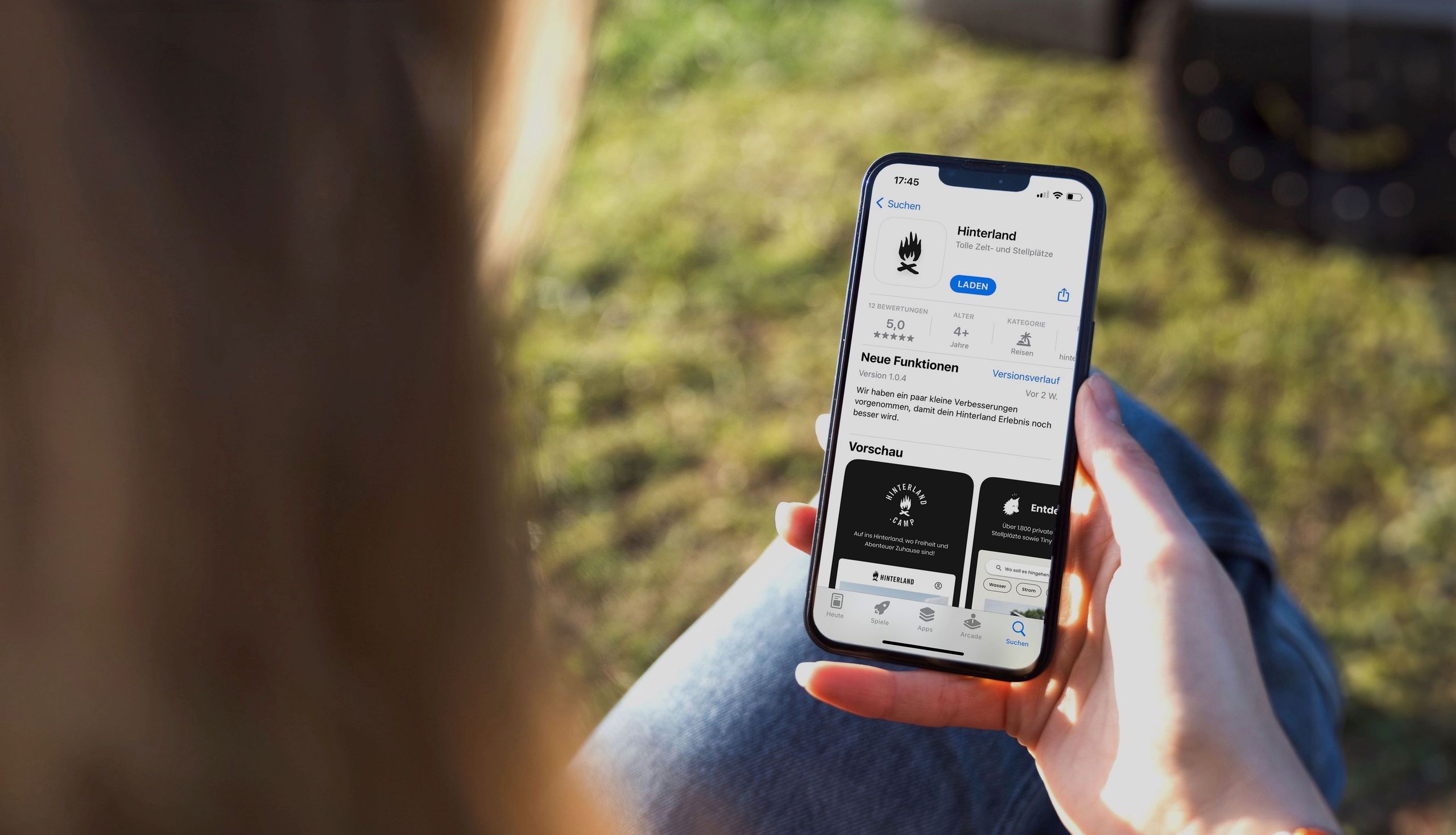 Hinterlands Camping-App ist auf einem IPhone zu erkennen, welches eine Frau in der Hand hält