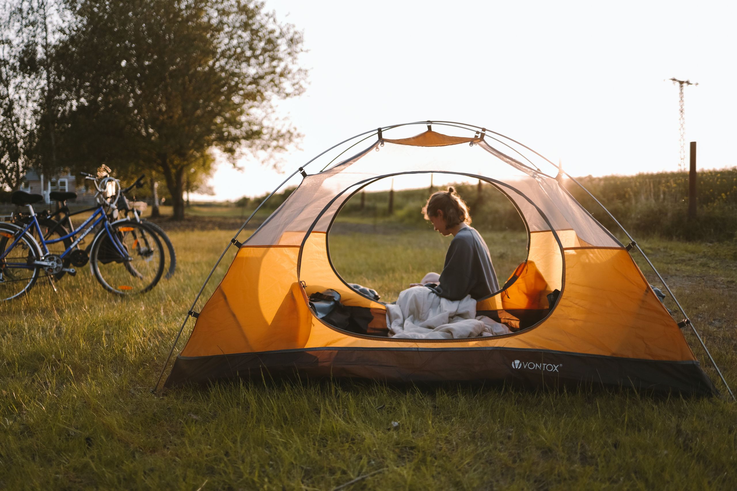 Frau sitzt in einem Zelt auf einem Stellplatz mitten in der Natur von hinterland.camp