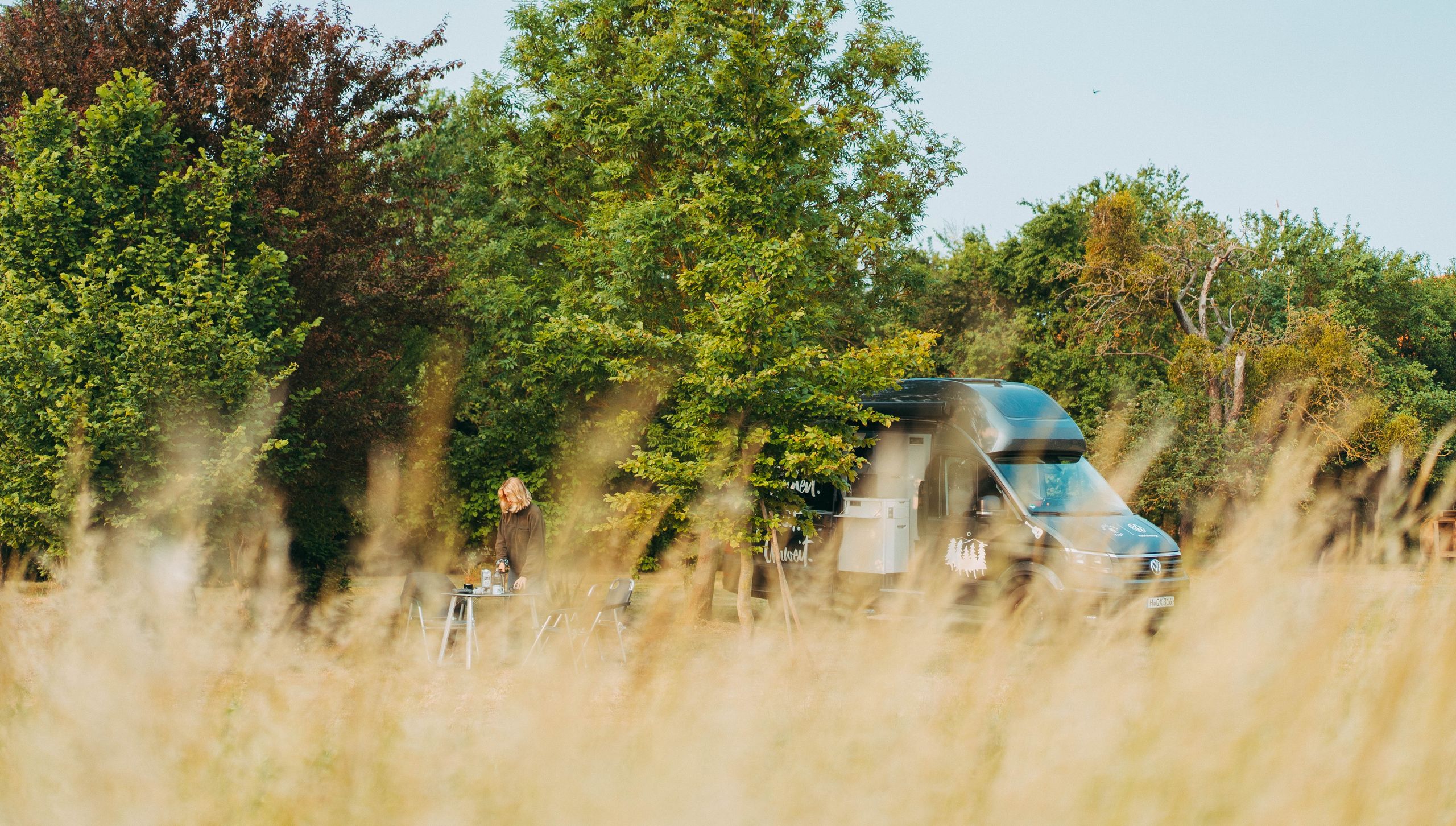Van steht auf einer Wiese im hohen Gras auf einem privaten Camping und Wohnmobil Stellplatz