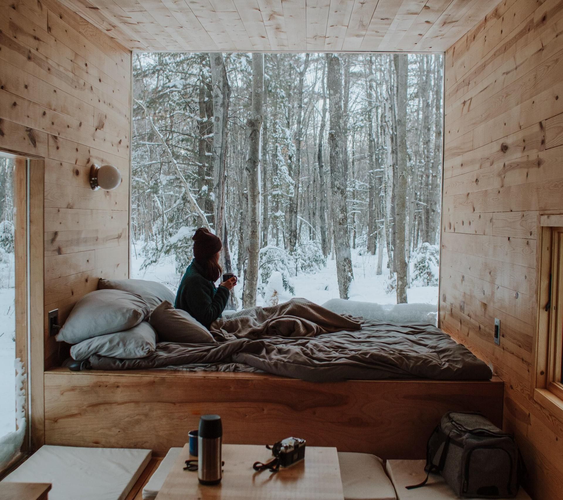Frau auf einem Bett in einer Holzhütte