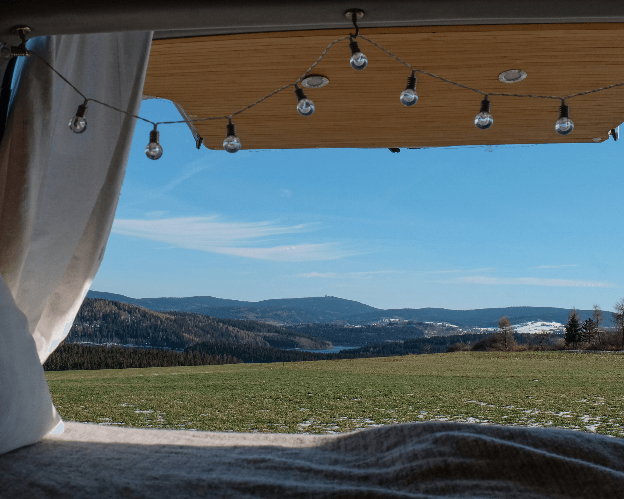 Blick aus dem Fenster eines Campers auf einen Stellplatz von hinterland.camp