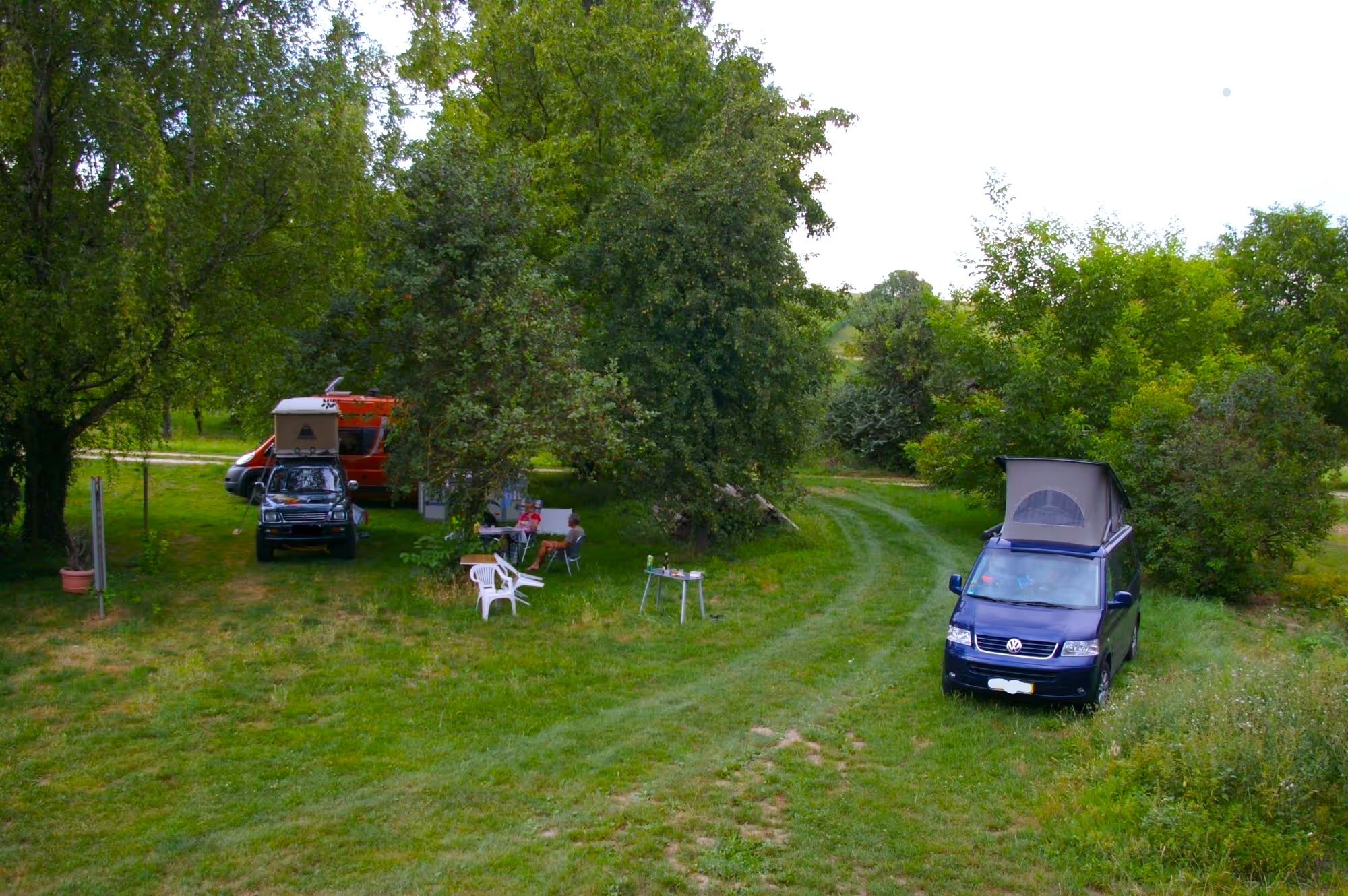 Zwei Camper stehen auf Camping Stellplatz von hinterland.camp auf einem Weingut im Münstertal mit Weinproben und einem schönen Blick in die Berge.