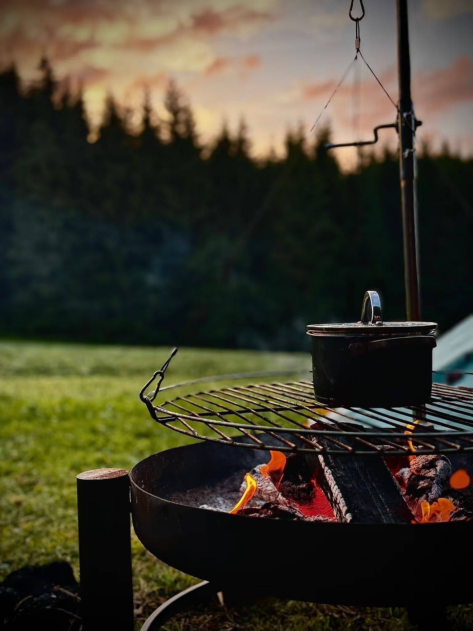 Ein Kochtopf steht auf einem Grillrost. Es wird essen zubereitet beim Münstertal-Camping auf einem Stellplatz von hinterland.camp.