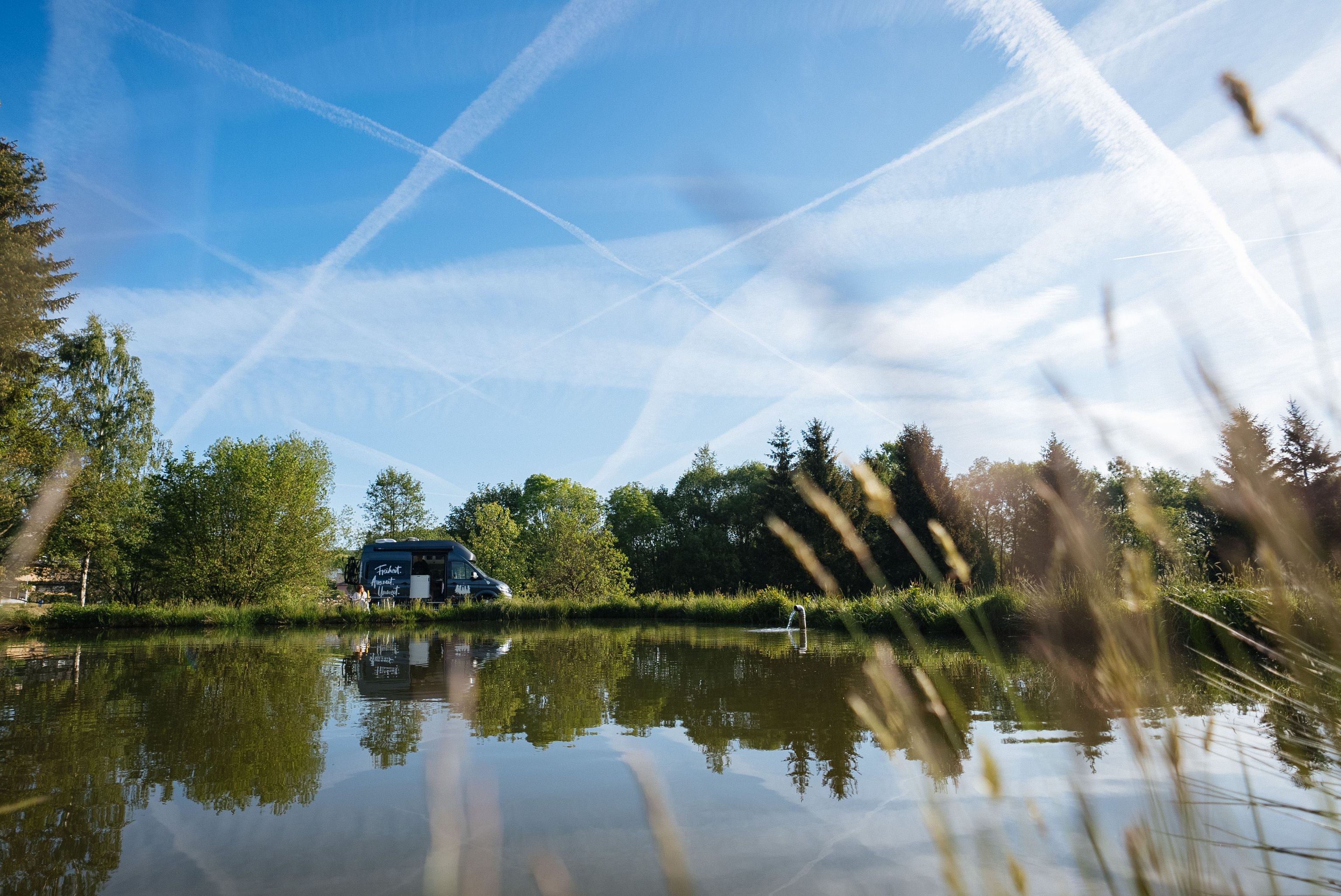 Camper steht auf einem Wohnmobil Stellplatz direkt am Wasser, buchbar bei hinterland.camp