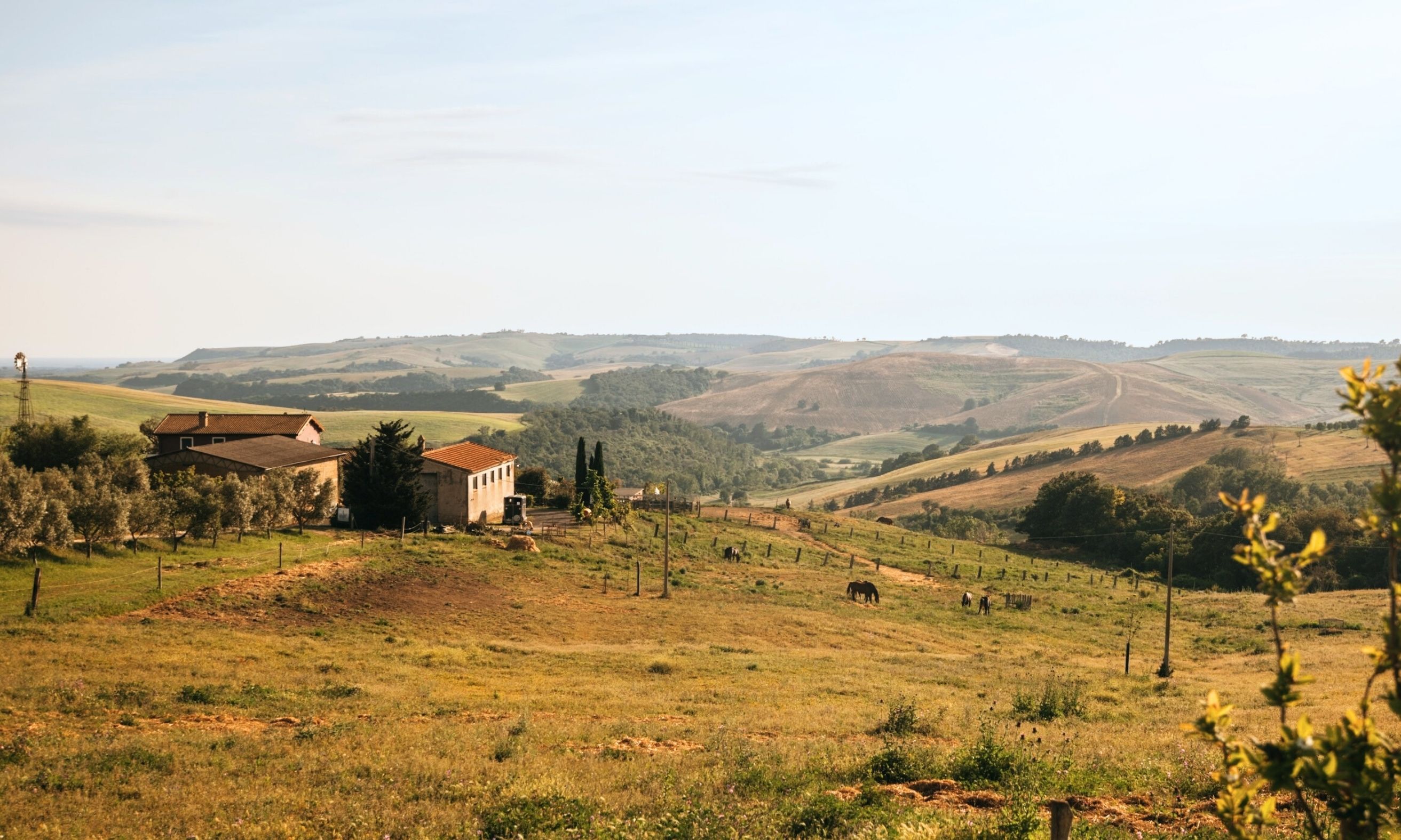 Man erkennt einen idyllischen Hof, der Camping Stellplätze anbietet. Im Hintergrund sieht man die hügelige Landschaft Italiens. 