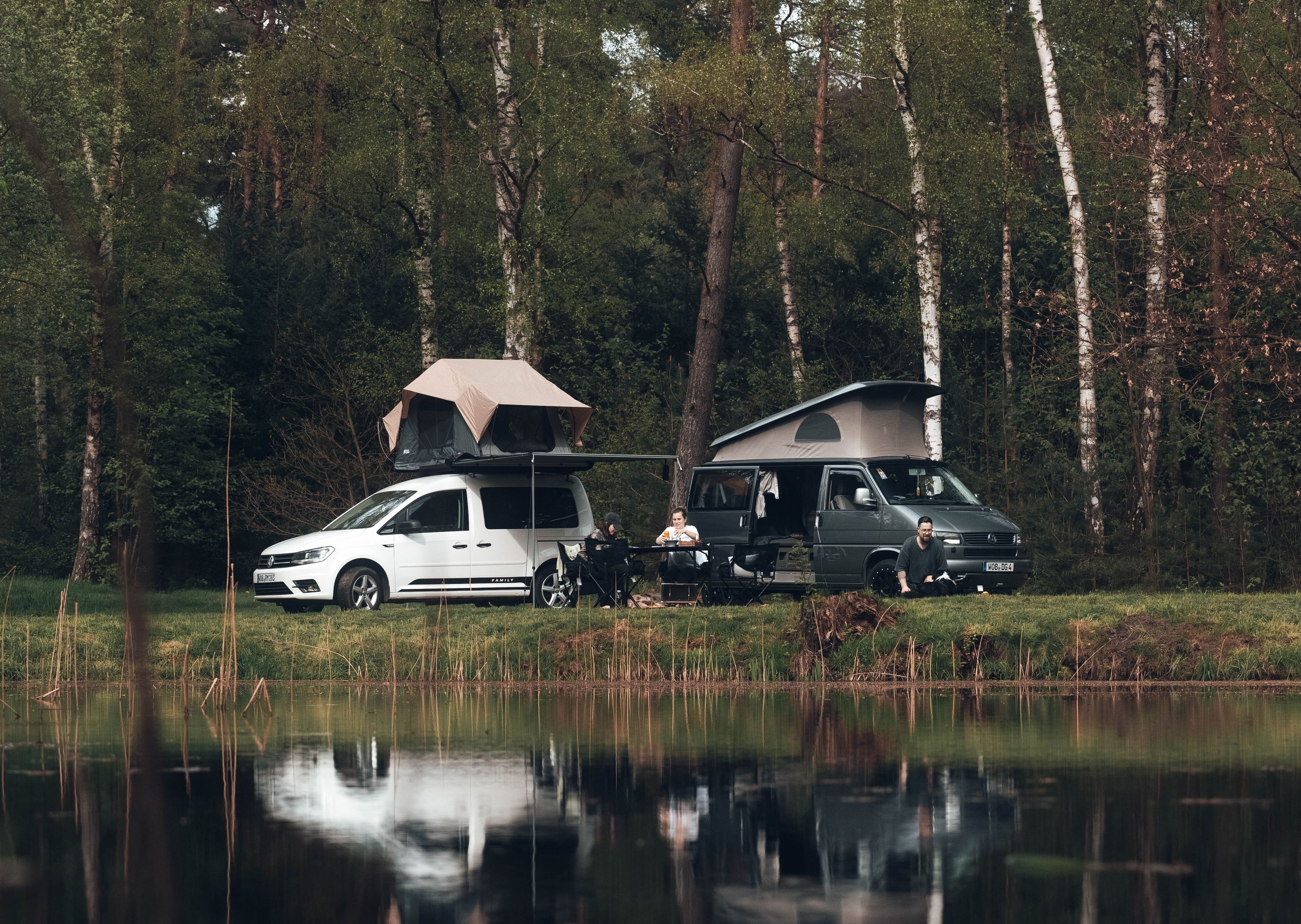 Zwei Camper stehen am Rande eines Sees mitten im Wald in Schweden. 