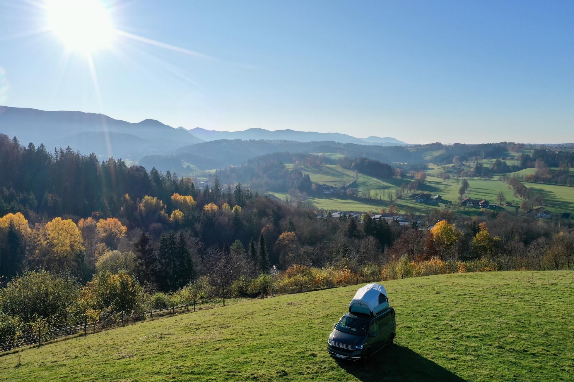 Camper mit Dachzelt steht auf einer grünen Wiese von Hinterland in Alleinlage mit toller Aussicht auf die Berge, den Wald und die schöne Natur