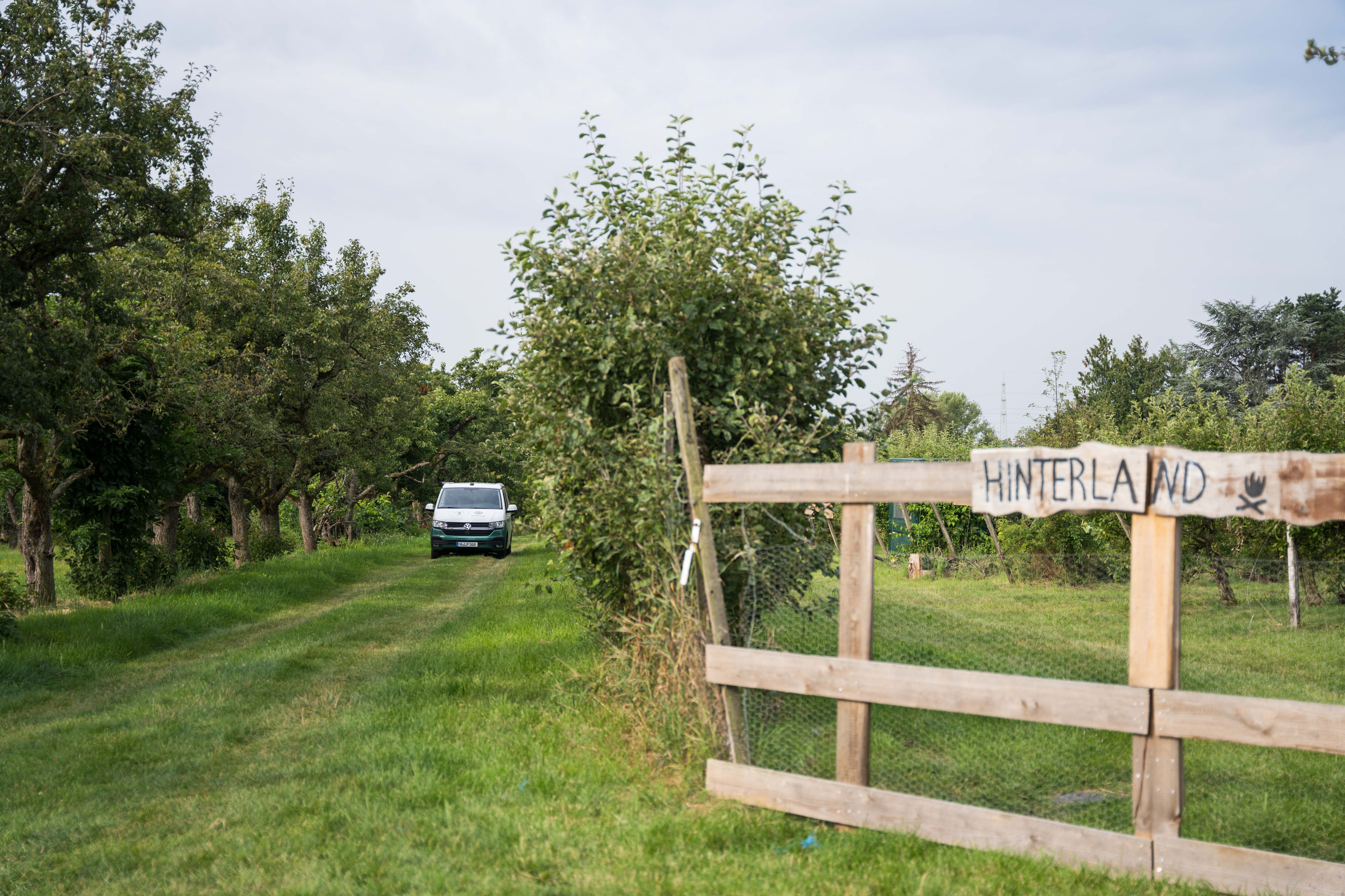 Ein Van steht mitten in der Apfelplantage auf einem Hinterland-Camp