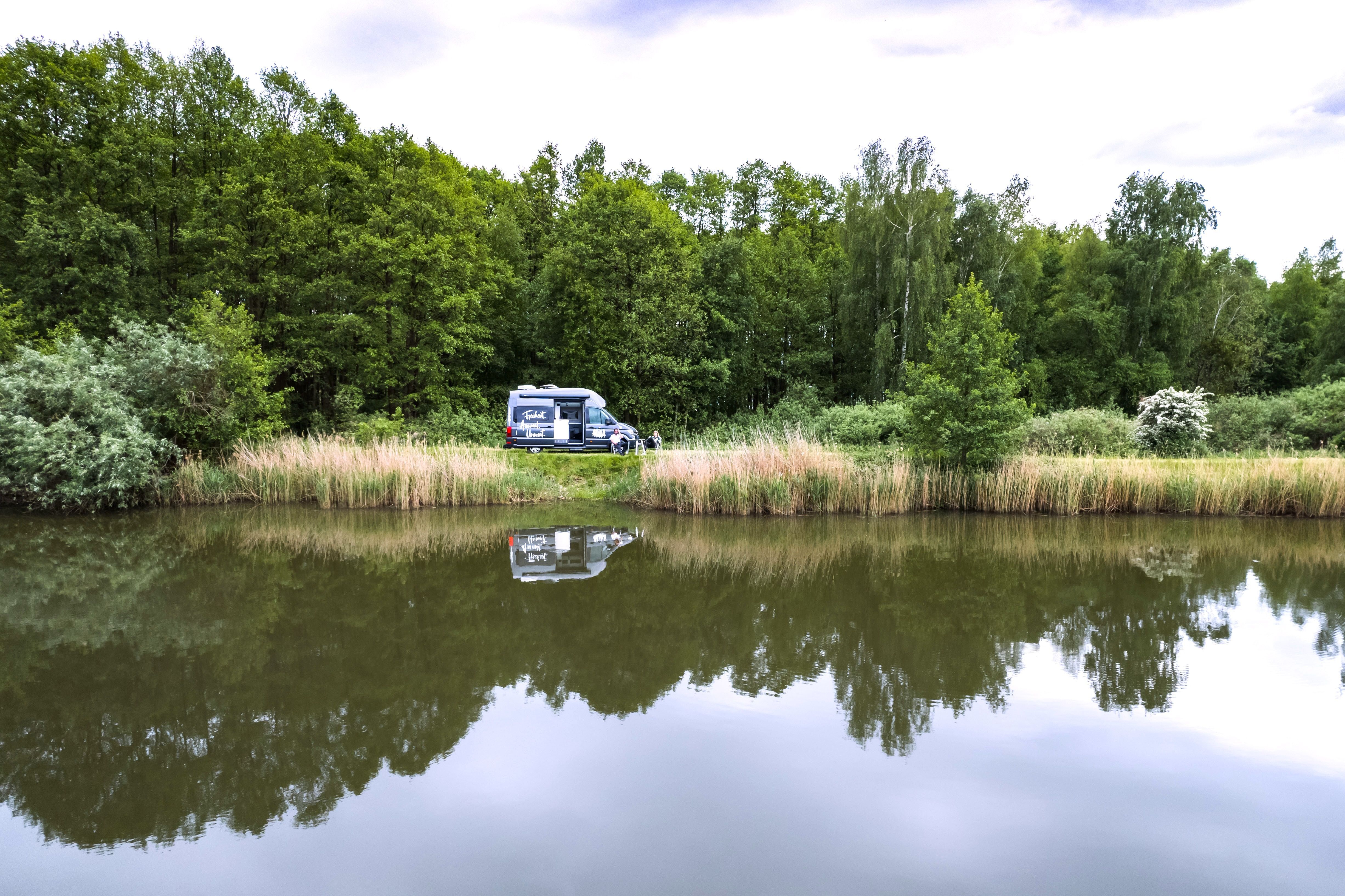 Ein Camper steht direkt an der Wasserkante eines Sees auf einem der schönsten Campingplätze Deutschlands