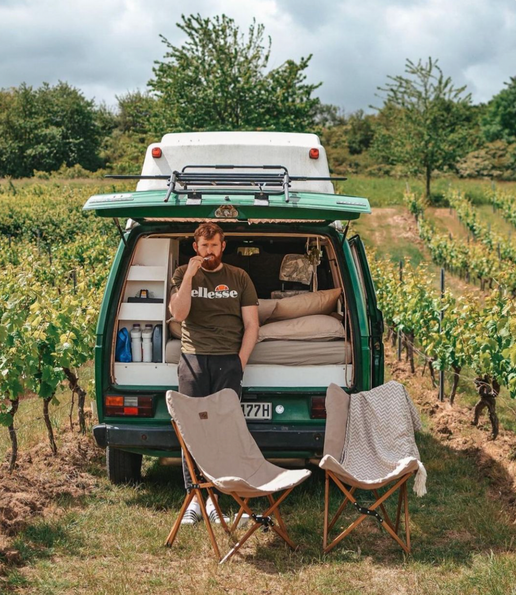 Camper von Hinter mit Stühlen vor dem Kofferraum