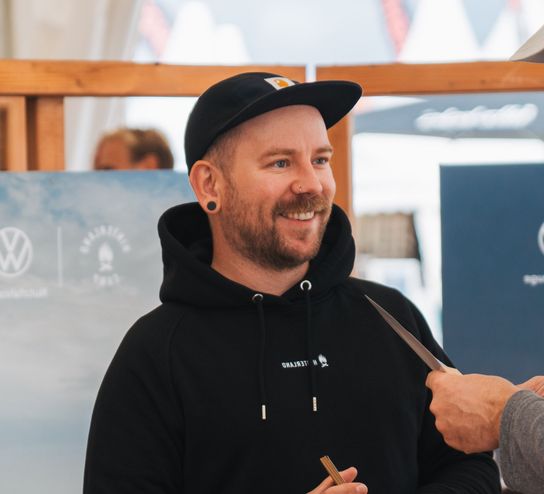 Ein lächelnder Steffen berät unsere Kunden von hinterland.camp auf einem Surfcup