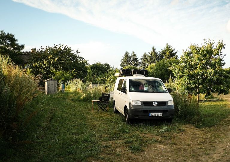 Bild von einem Camper, der auf einer natürlichen Wiese unweit der Ostsee liegt, der Stellplatz ist bei hinterland.camp buchbar