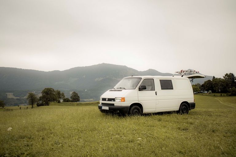 Ein weißer Camper steht vor den Bergen in Bayern. Man kann den Campingplatz online bei hinterland.camp buchen.