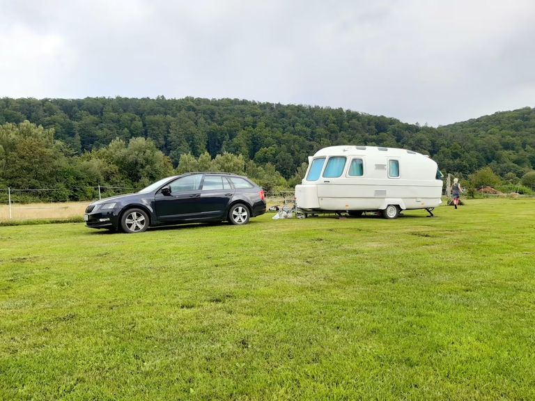 Ein Auto und ein Wohnwagen stehen auf einer Wiese, die zu einem der schönsten Campingplätze Deutschlands zählen