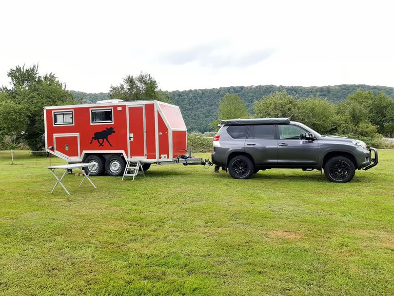 Ein Auto und ein Wohnwagen stehen auf einer Wiese, die zu einem der schönsten Campingplätze Deutschlands zählen