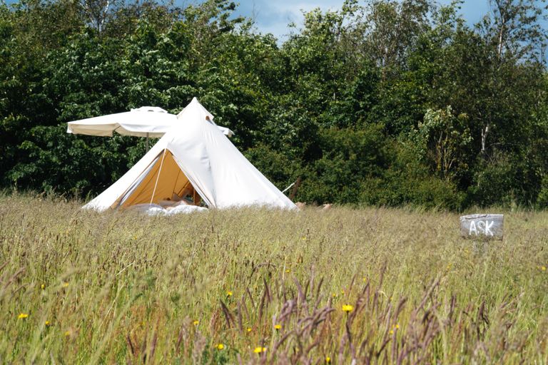 Foto eines gemütlichen Glampingzeltes mit einem Bett und Stühlen, in dem man übernachten kann. Die Übernachtung kann man auf hinterland.camp buchen.