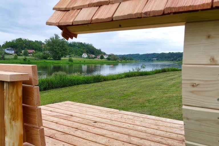 Schöner Blick über die Elbe. Angeschnitten sieht man im Vordergrund das Dach des Shelters in der Nähe von Dresden, den man für eine Glamping-Übernachtung bei hinterland.camp buchen kann.