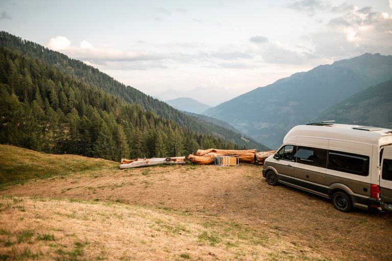 VW-Camer steht auf einem Campingplatz mit atemberaubendem Blick in die Alpen