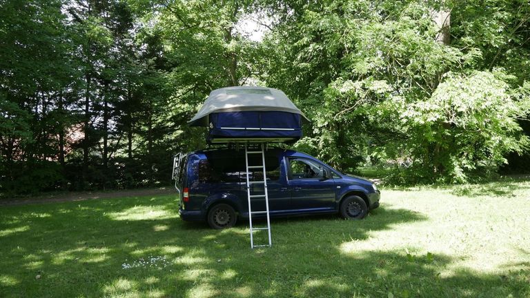 Camper steht auf einem idyllischen Stellplatz vor einem Gutsahof auf einem Wellness-Campingplatz von hinterland.camp