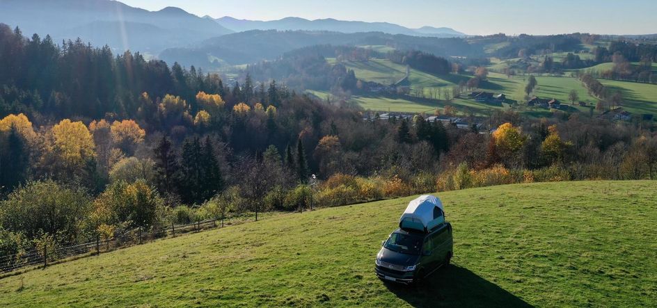 Camper mit Dachzelt steht auf einer grünen Wiese von Hinterland in Alleinlage mit toller Aussicht auf die Berge, den Wald und die schöne Natur